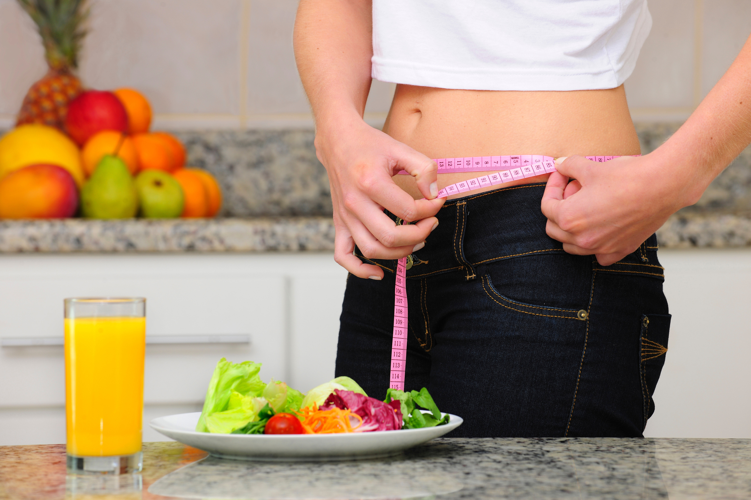 diet: woman with salad and measuring tape